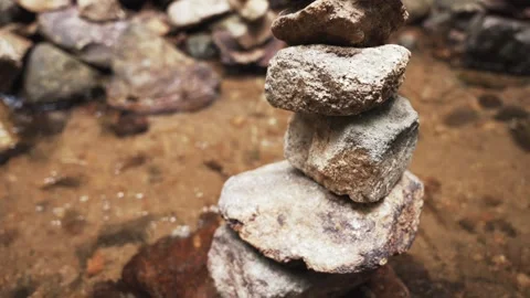 Tilt slow motion of Zen-style stone tower in a shallow jungle river stream 動画素材 309276815