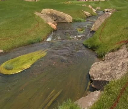 Tilt up as stream flows through golf course Stock Footage 21678405