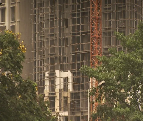 Tilt up, then down scaffolding and crane on high-rise under construction. Video stock 86742585
