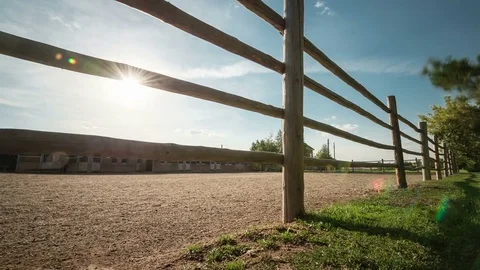 Tilt-up time lapse of operating horse-breeding farm surrounded by a wooden fence Video stock 75332027