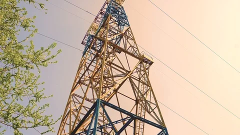 Tilt up view on transmission tower supporting overhead power line against sky Stock Footage 106997507