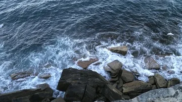 Tilt view of waves hitting cliffs, revealing the south pacific ocean, on a su Stock Footage 85727231