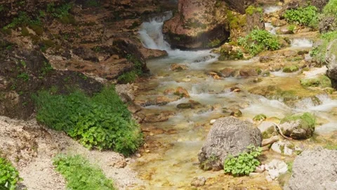 Tilt up to a waterfall surrounded by gold-colored stones Stock Footage 283342207