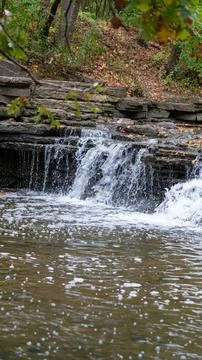 Tilted Cascade: Blurred Waterfall with Foaming Stream and Foreground Branch Stock Photos