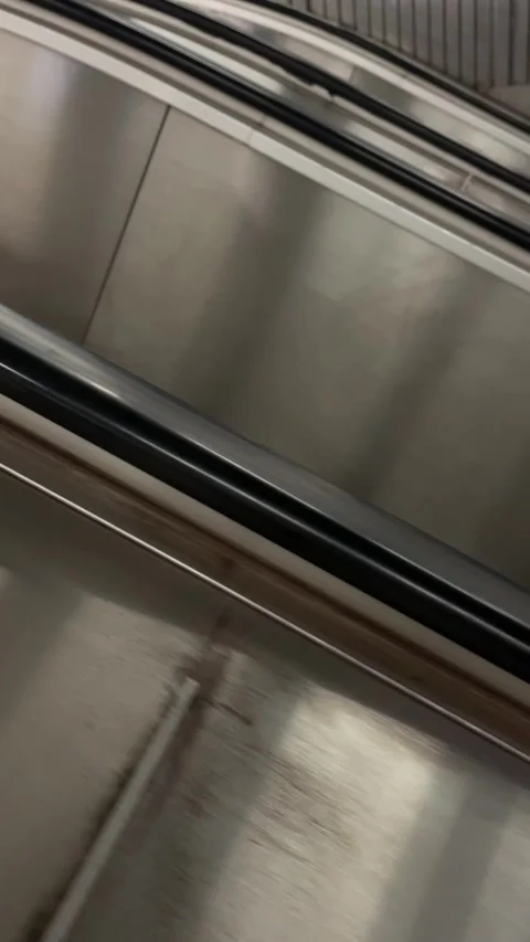 Tilted closeup of black handrails crossing brushed stainless steel elevator Vidéo 341662685