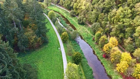 Tilted drone fly at winding water channel flowing through on green Concise Stock Footage 321189444