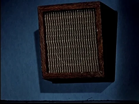 Tilted face speaker box with brown wood cabinet mounted on blue wall - 1960 Stock Footage 107361556