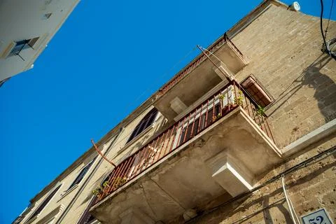 Tilted low angle view of an old stone building with a rusty wrought iron balcony Fotos de archivo