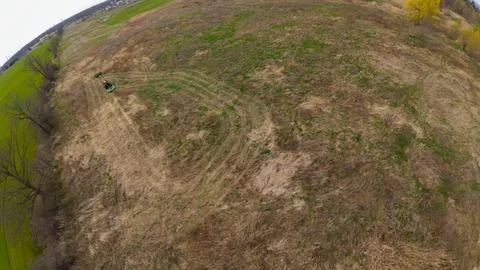 Tilted overhead aerial view of a tractor working a rough meadow Stock Photos