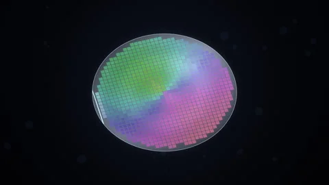 Tilted rainbow semiconductor wafer spins as a scan beam lights its chip die.. Stockbeeldmateriaal 346958657