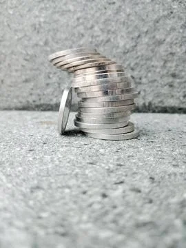 Tilted Stack of Coins with One Coin Leaning on the Edge Stock Photos