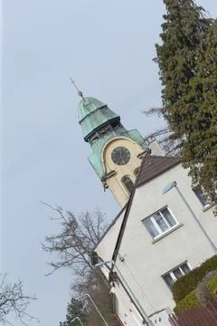 Tilted view of a small church tower with copper dome beside residential building Stock Photos