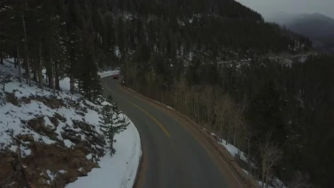 Tilting camera up from a snowy mountain road to the misty peaks above Stock Footage 167675286