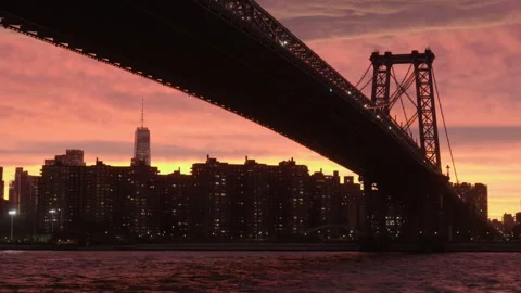 Tilting up to closer sunset view of downtown NYC under Williamsburg Bridge Stock Footage 346427912