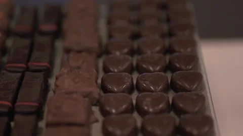 Tilting closeup shot of assorted heart-shaped and rectangular chocolates at a 스톡 동영상 325359521
