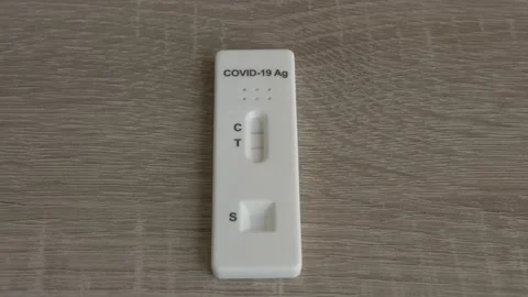 Tilting down fast to slow to a Covid-19 positive antigen test on a wooden table Stock Footage 152000252