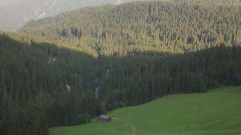 Tilting down to reveal a dense forested area surrounding an isolated farming Stock Footage 307707382