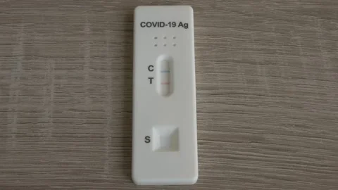 Tilting down slowly to a Covid 19 positive antigen test on a wooden table Stock Footage 152000275