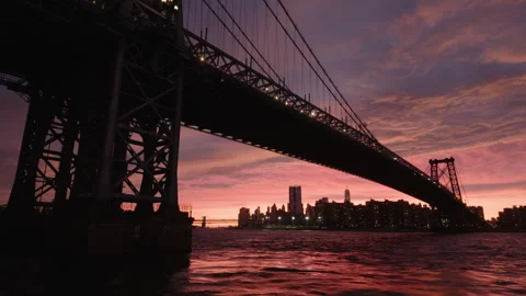 Tilting down to sunset view of downtown NYC under Williamsburg Bridge Stock Footage 346427960