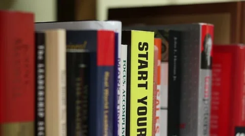 Tilting down then up on the spines of business books Stock Footage 48475893