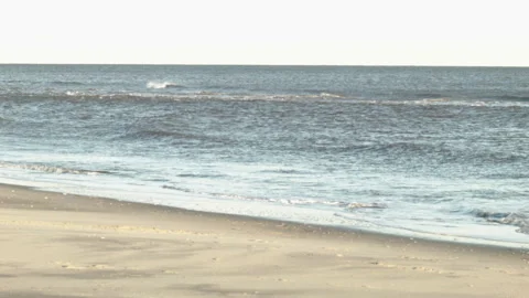 Tilting from Sand to Ocean Waves at Sunset on a Quiet Beach Stock Footage 185096145