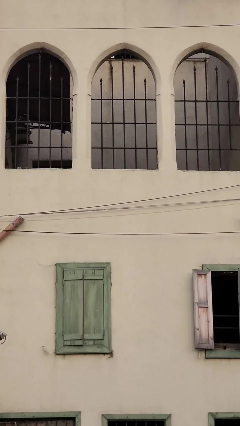 A tilting shot moving up an old building with a green door and arched windows Stock Footage 314172672