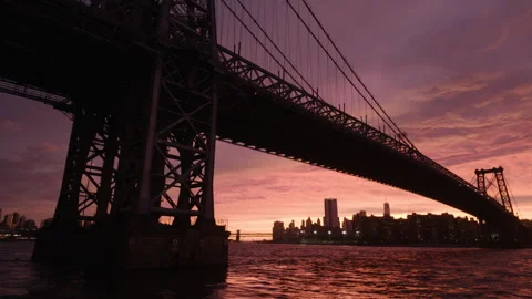 Tilting up to sunset view of downtown NYC under Williamsburg Bridge Stock Footage 346427536