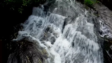 Tilting view down along waterfall from it creek Stock Footage 158326169