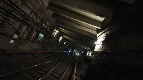 Tilting view down a dimly lit underground railway tunnel with converging tracks Video stock 333051229