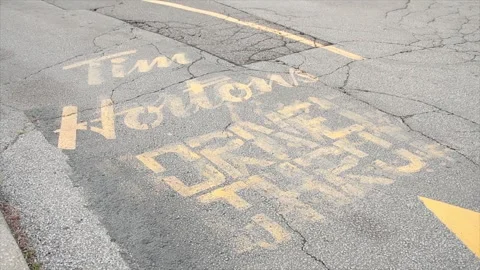 Tim hortons drive thru written text caption on pavement in yellow with logo Stock Footage 249760626