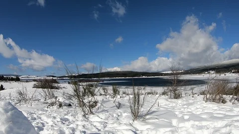 Tim lapse of fast moving white clouds over a frozen lake Stock Footage 119501380