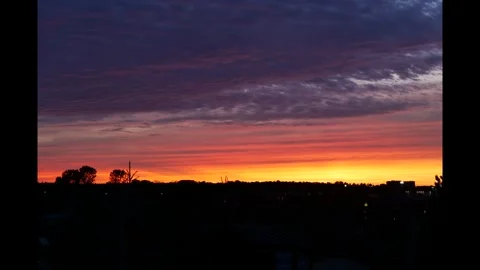 Tima lapse of sunset turns clouds fiery orange in a purple sky. Stock Footage 313641253