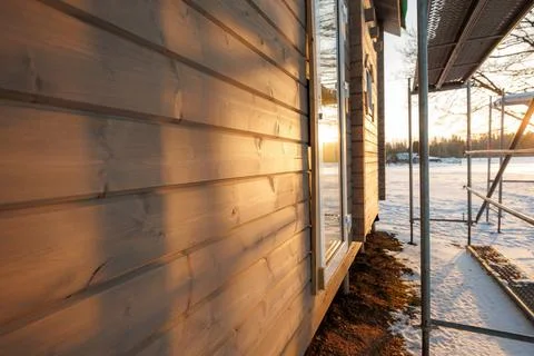 Timber cabin cladding in winter sun with door ajar and scaffolding Stockfoto's