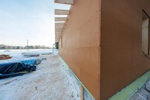 Timber clad house shell under construction on a snowy rural site Stock Photos