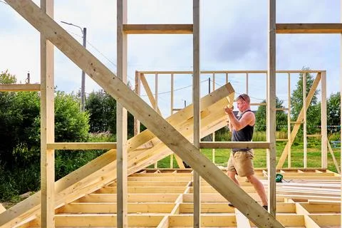 Timber frame construction, worker manually raising a prefabricated timber w.. Stock Photos