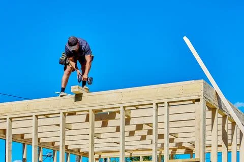 Timber frame construction with young worker fastening roof boards using cor.. Stock Photos