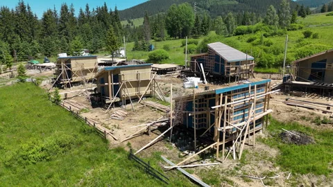 Timber framed buildings under construction stand in a mountain meadow, Remote 库存影片 344662961
