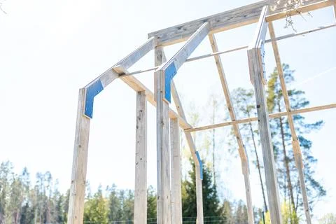 Timber greenhouse frame with blue brackets at outdoor build site 스톡 사진
