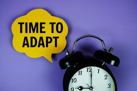 Time To Adapt text on speech bubble with alarm clock on purple background Stock Photos