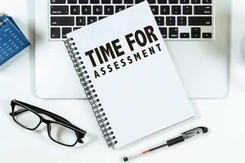 Time For Assessment text on notepad with laptop on office desk. Stock Photos
