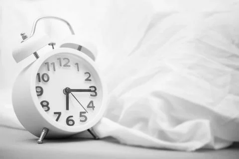 Time background concept. Alarm clock on bed, wake up in the morning. Picture Stock Photos