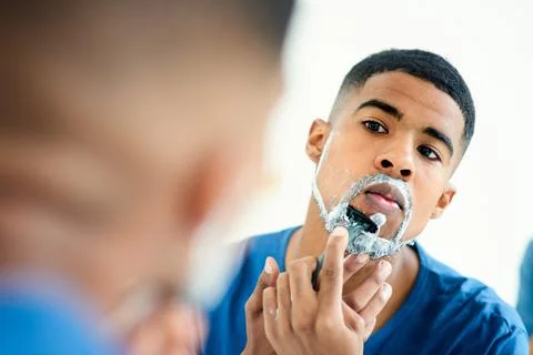 Time to be clean shaven for a while again. a focused young man checking his Stock Photos