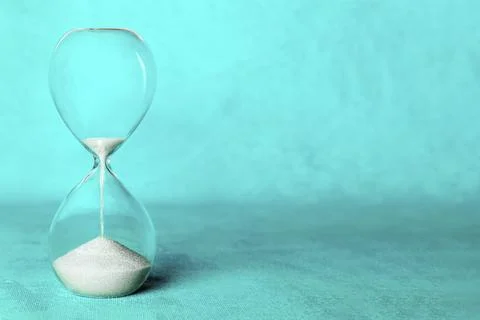 Time concept. An hourglass with sand falling through, on a vibrant blue 스톡 사진