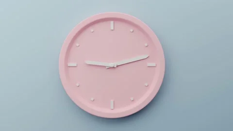 Time concept. A pink clock with white arrows hanging on a gray-blue wall. The Stock Footage 132229959