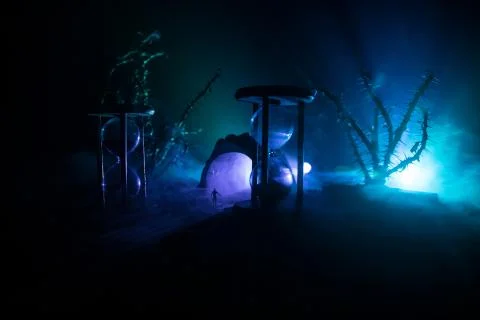 Time concept. Silhouette of a man standing between hourglasses with smoke and Stock Photos