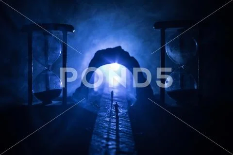 Time concept. Silhouette of a man standing between hourglasses with smoke and Stock Photos