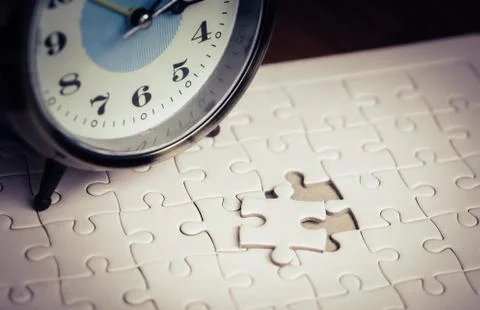 Time counting down on alarm clock to palce the last jigsaw Foto stock