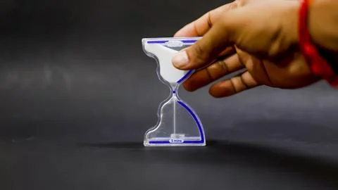Time discipline concept with hand flipping glass sand timer Stock Photos