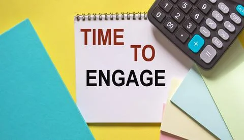 Time to engage , text on a notebook, next to a calculator, stickers and a dia Stock Photos