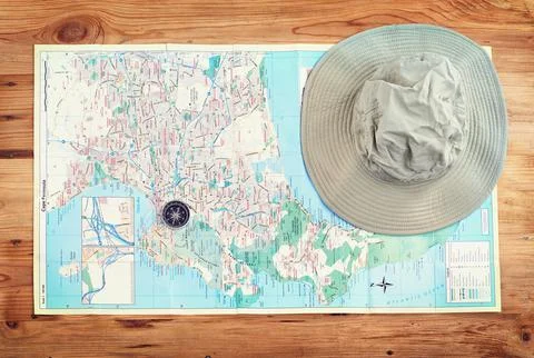Time to explore. a compass and a hat lying on a map on a table. Stock Photos